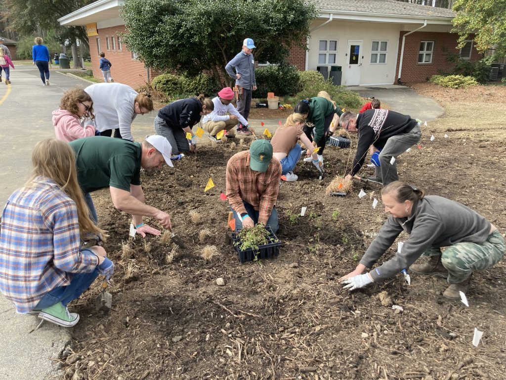 Teens, chaperones, and NCBG staff plant native pollinator species in a new garden outside the Museum of Life and Science