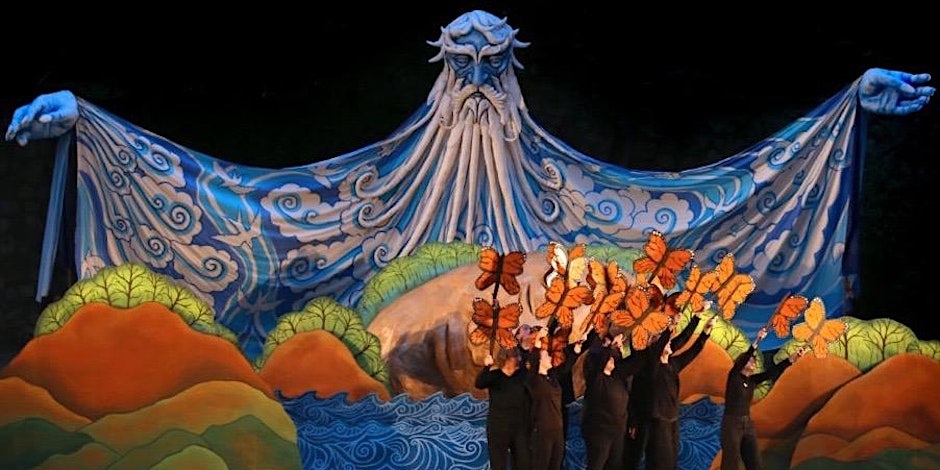 A giant paper puppet of the ocean stands behind monarch butterfly puppets