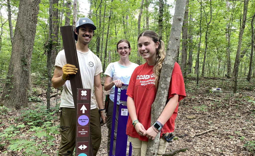 Summer interns and the Garden's natural areas steward pose next to new trail markers they installed at Battle Park.